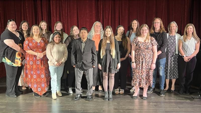 group of 16 people standing on theatre stage